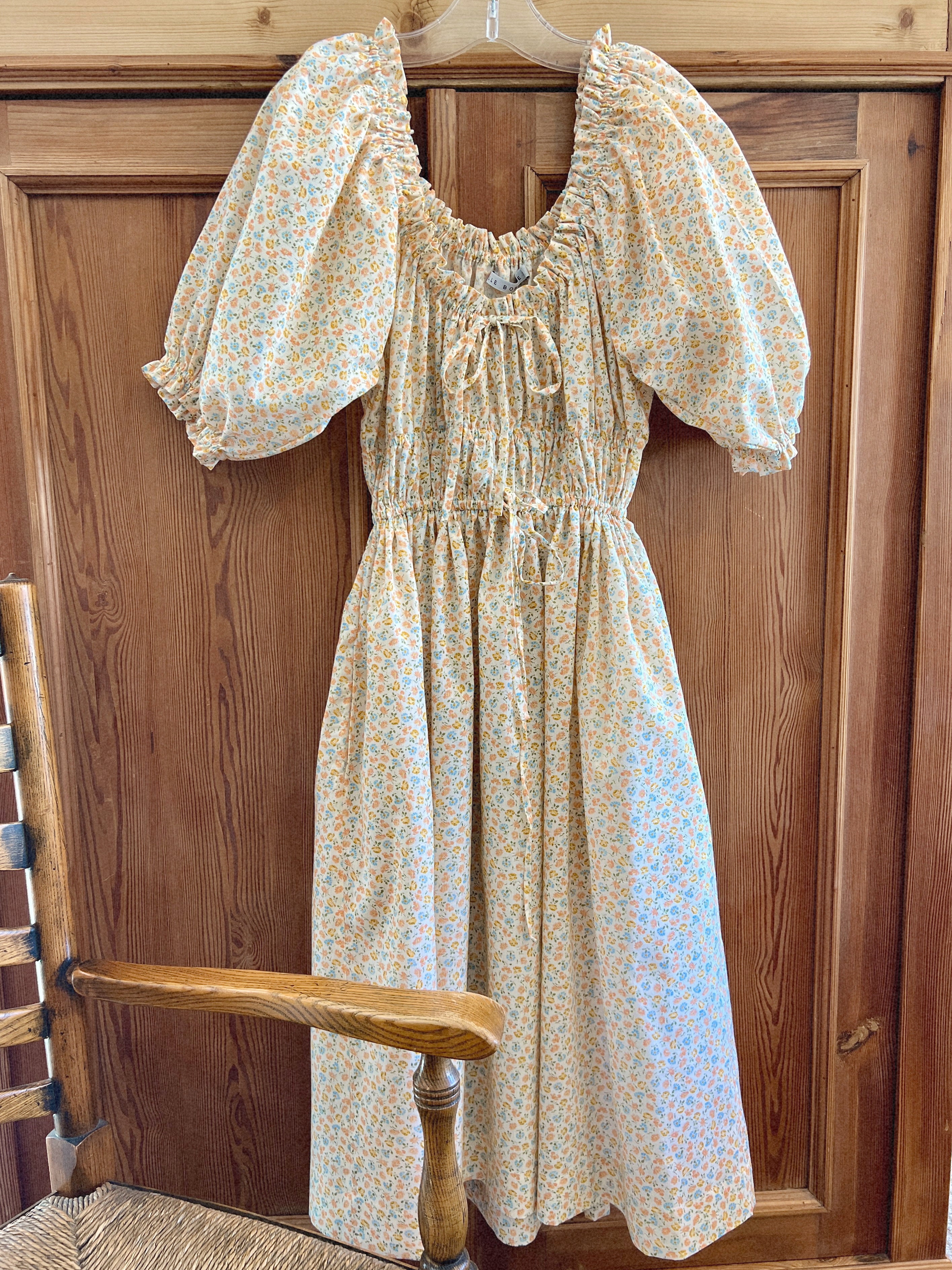 cotton floral dress with puffed sleeves hanging on a wooden door