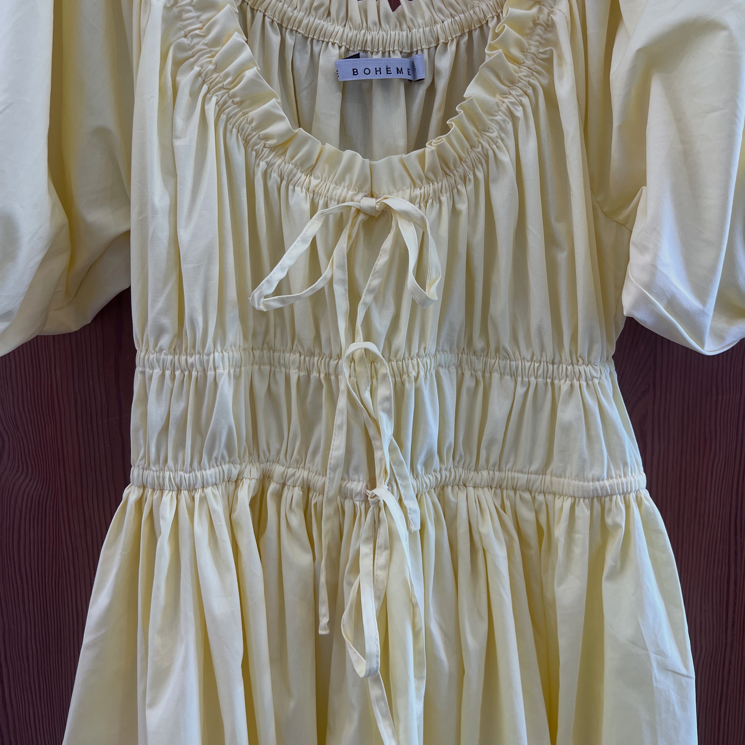 close up of freewind dawn butter yellow midi dress featuring  adjustable scoop neckline adjustable drawstring waist and elle boheme label sew on. 