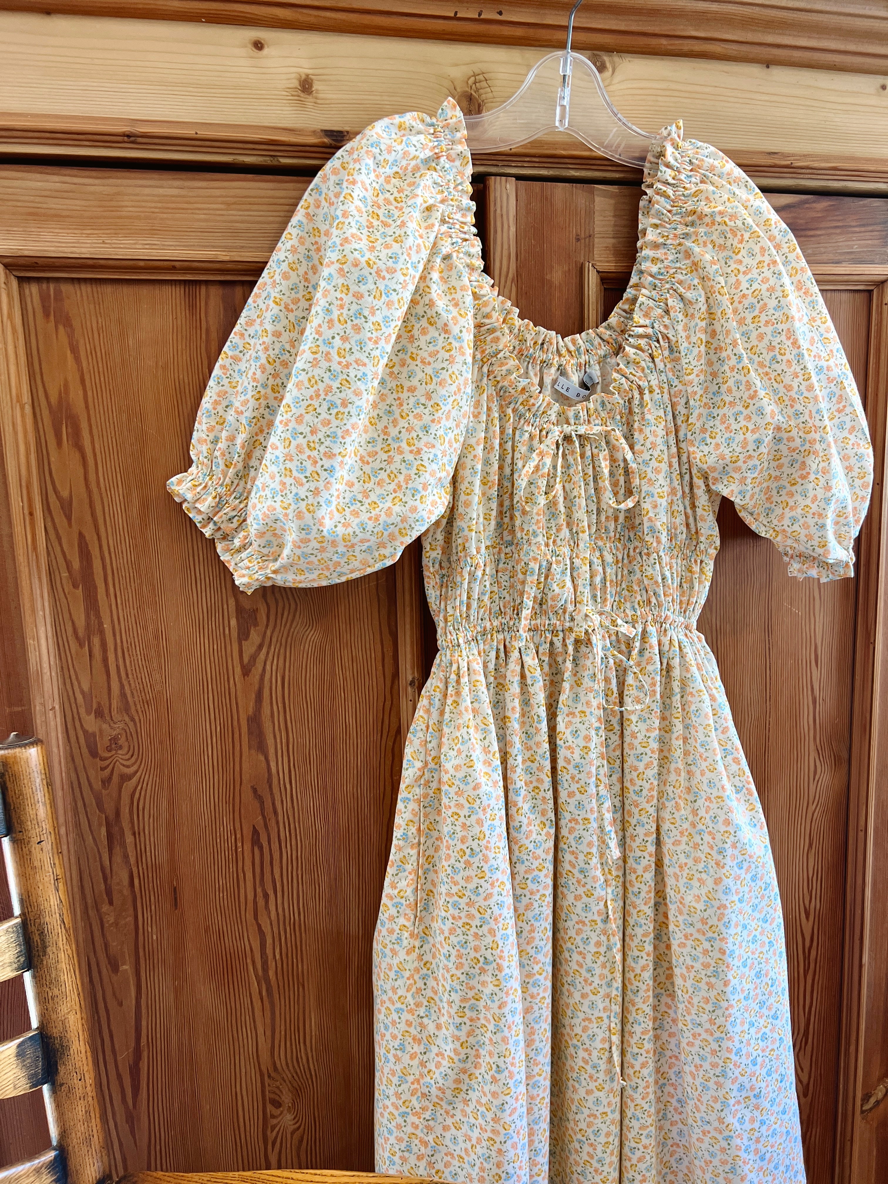 Elle boheme one of a kind floral midi dress with puffed sleeves and adjustable drawstring waistband hanging on a wooden baltic pine wardrobe door