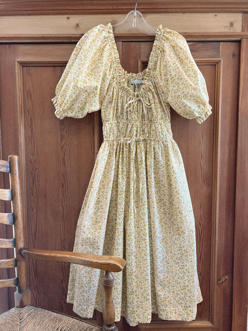 Elle boheme vintage inspired silouette wildflower pattern midi dress hanging on a  english cottage background